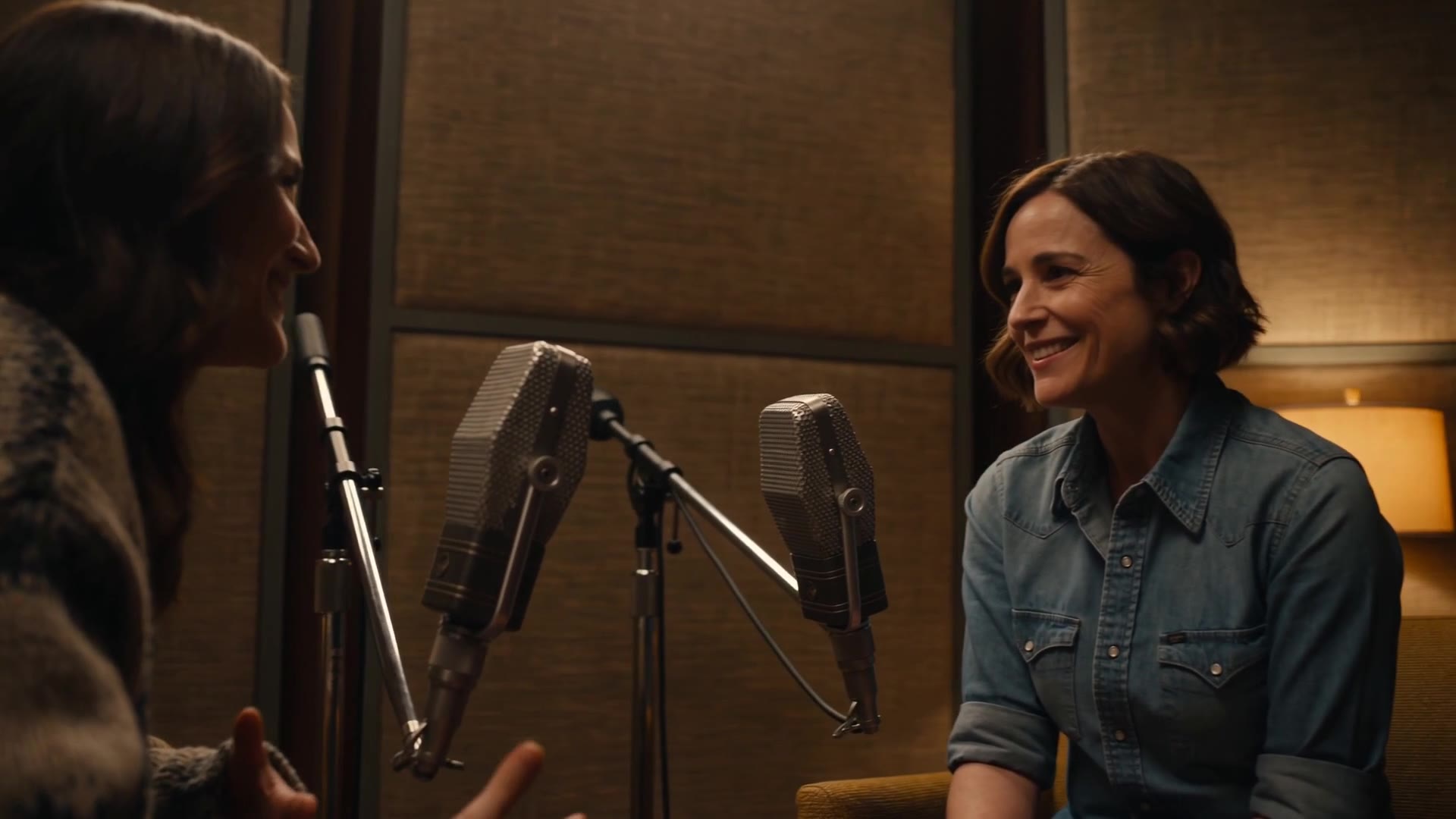 Episode 001 still — two hosts in conversation in a warm studio, a dog asleep at their feet
